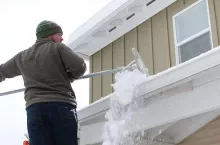 39705086 - caucasian man using rake to shovel heavy snow off roof