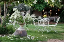 White table and chairs in beautiful garden.