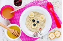 Oatmeal porridge bear with honey banana and berries, fun food art idea for the kids breakfast top view