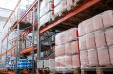 Canisters covered with stretch wrap placed on pallets at storage room, metal frame with items
