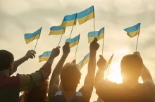 Crowd with ukrainian flags in the evening. Ukrainian revolution. Evening sunny sky background.