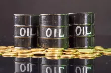 Barrels with oil and golden coins on the reflective desk. Oil money concept.