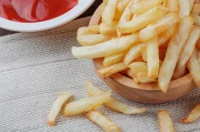 French fries in a bowl and sauce on tablecloth.