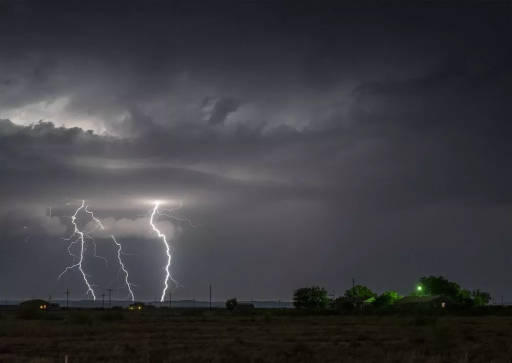 A large lightning strike at night in a rural area of Roswell, New Mexico framed against stormy skies.