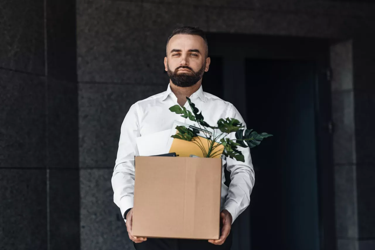&lt;p&gt;Unemployed man moving out office center with box full of personal stuff, looking sadly to camera. Businessman walking along office building, lost job and left without money&lt;/p&gt;