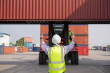 Back view of engineer foreman controlling container forklift at warehouse port. Logistic business. export import goods. shipping and delivery at dock