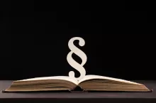 paragraph sign and open book on black stone background