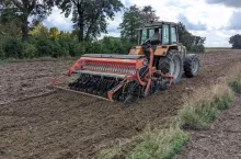 Rolnik w ciągniku z siewnikiem na polu