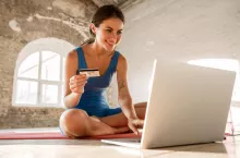 &lt;p&gt;Beautiful smiling sportswoman using credit card and laptop while sitting on mat indoors&lt;/p&gt;