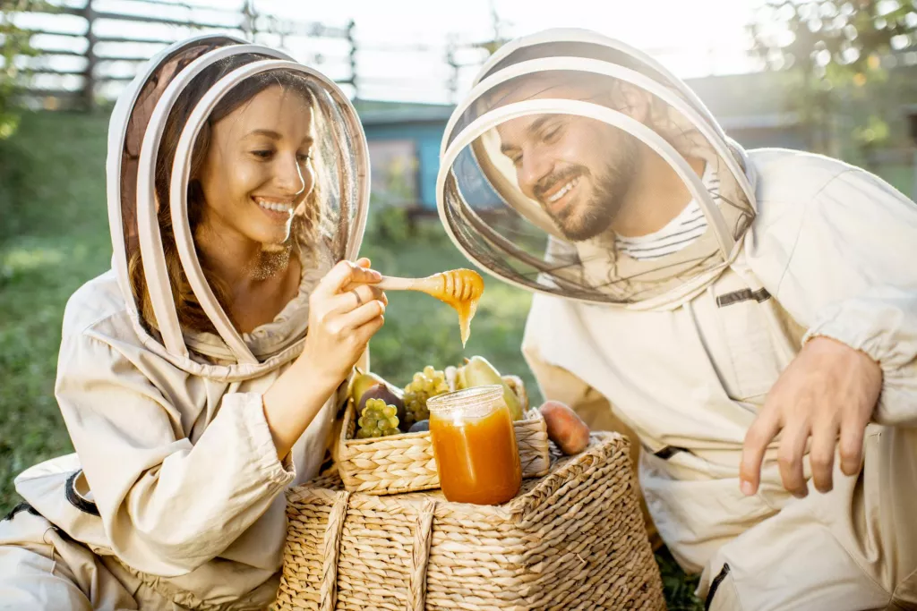 &lt;p&gt;Portrait of a two cheerful beekeepers in protective uniform with honey products and sweet fruits on the apiary on a sunny evening&lt;/p&gt;