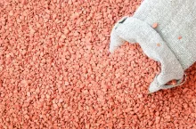 Bag and chemical fertilizer for the plant, place for text. Red fertilizer background potassium chloride.