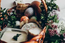 happy easter. easter basket with cake and eggs ham food. colorful decorated egg with floral and chicken ornaments and lilac flowers. space for text. rustic greeting card