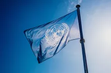 UN flag waved against the sun and blue sky.