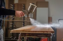 Mężczyzna zabezpieczający drewno pistoletem natryskowym