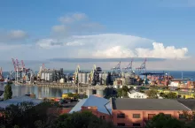 Port harbor with grain elevator terminal and red warehouse building rooftops. Sea view with heavy machinery loaders. Industrial landscape of European Black sea coast