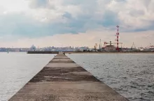 Chornomorsk, Ukraine - 04 20 21: Sea port. Cranes, boats and other industrial constructions, pier road going into perspective. Dramatic evening sky.
