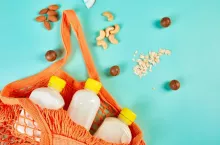Grocery, shop Various vegan plant based milk, non-dairy milk, alternative types of vegan milks in bottle in shopping bag on a blue background, flat lay, top view with copy space