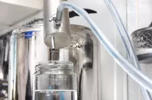 Silver distillation machine is standing on the burner in the kitchen. Home alcohol product. Cooking moonshine in the kitchen.