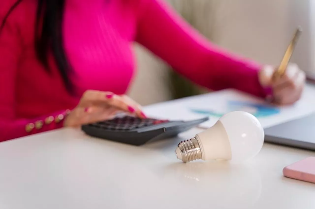Crop anonymous female freelancer in pink sweater sitting at table with laptop and working on project