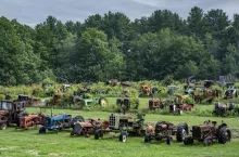 A field of obsolete old and rusted tractors along a roadside in Maine.