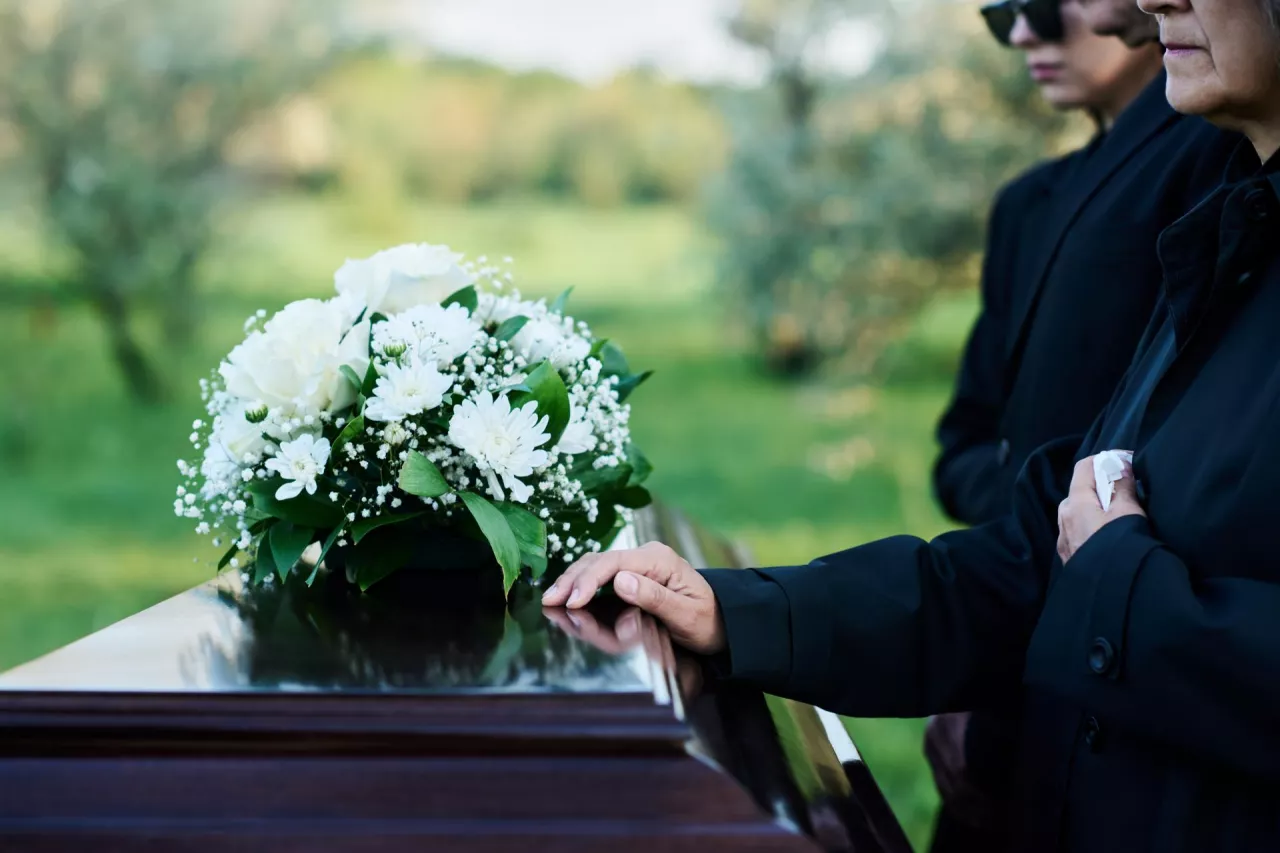 &lt;p&gt;Cropped shot of mature woman and her family in mourning attire standing in front of coffin with closed lid with fresh white chrysanthemums&lt;/p&gt;