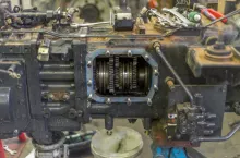 Gears inside a tractor gearbox. The side cover plate has been removed to expose the internal gears and syncros. Tools are layed on top of the gearbox.
