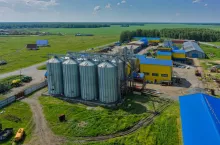 Novikova, Russia - June 18, 2015: Aerial view onto modern machine yard of agricultural firm Russian Field. Corn dryer silos standing in machine yard. Tyumen region