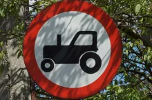 one round road sign the tractor is prohibited, on the street in green vegetation