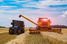Agriculture process in wheat field during the sunny day with blue sky. Heavy technics. Rural landscape. Harvest time