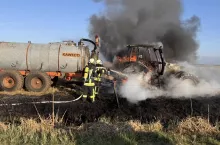 Strażacy podczas działań gaśniczych palącego się cięgnika rolniczego na polu