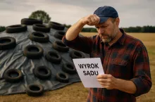 Fotorealistyczna ilustracja przedstawiająca rolnika stojącego przy dużej pryzmie kiszonkowej zabezpieczonej oponami. Mężczyzna zafrasowany czyta kartkę z napisem ”Wyrok sądu” i przeciera czoło. Obraz oddaje konflikt między rolniczą praktyką a przepisami dotyczącymi przetwarzania odpadów. Tło stanowi otwarty wiejski krajobraz z polami i lekkim zachmurzeniem.