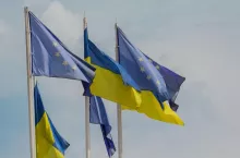 Ukrainian and European Union flags develop on sky background