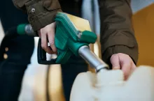 Close-up of woman filling plastic gallon with fuel at a gas station.