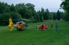 Strażacy transportują rannego do helikoptera Lotniczego Pogotowia Ratunkowego.