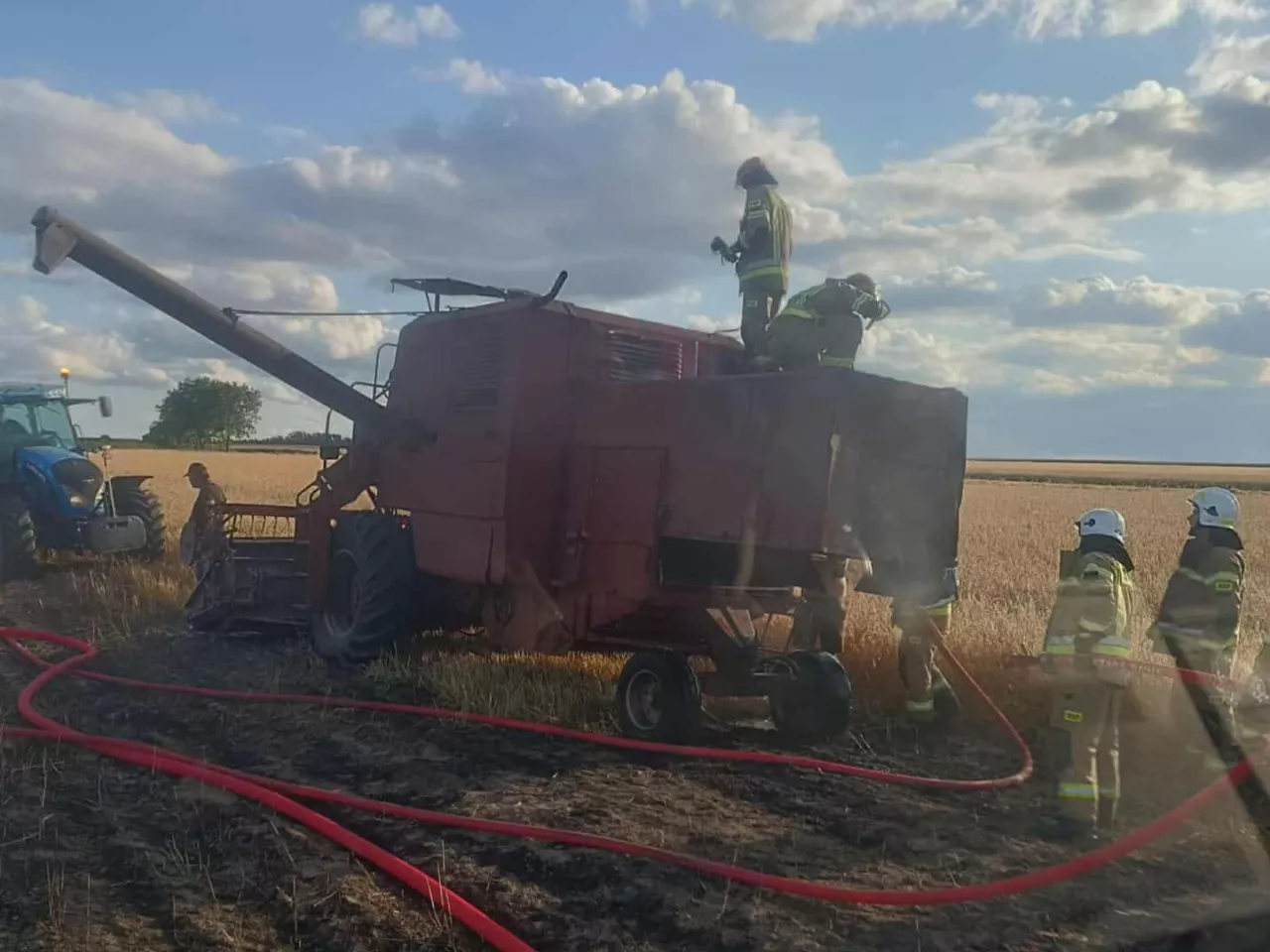 Strażacy podczas akcji gaszenia kombajnu na polu