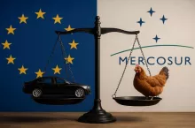 Symboliczne przedstawienie skutków umowy UE–Mercosur: na jednej szali samochód reprezentujący eksport przemysłowy z Unii Europejskiej, na drugiej żywy kurczak symbolizujący import produktów rolnych z Mercosur. Tło tworzą flagi UE i Mercosur.