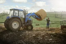 Farming brothers driving tractor moving hay stack on dairy farm