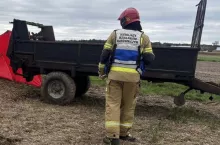 Strażak w ubraniu specjalnym stojący przed rozrzutnikiem obornika