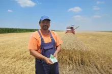 Farmer holding Euro banknote with combine harvester in background