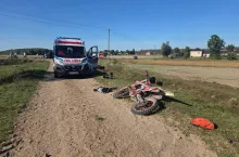 Motocykl typu cross na bocznej drodze, a w tle karetka pogotowia