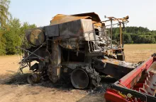 Burnt out combine harvester in field