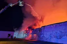 Strażacy z podnośnika polewają palący się budynek kurnika