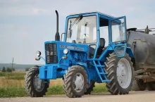 Niebieski ciągnik Belarus MTZ-82 na polnej drodze.