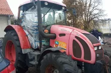 Czerwony ciągnik rolniczy na parkingu bez jednego skrzydła drzwi