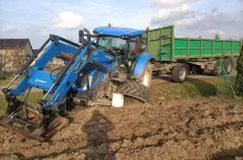 Rozbity ciągnik rolnicy New Holland z przyczepą w rowie