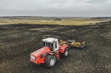 Traktor pracujący na szerokim polu czarnoziemu. Krajobraz typowy dla dużych areałów Ukrainy, gdzie dominują uprawy w monokulturach i intensywna produkcja roślinna.