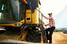 Harvester machine driver climbing into a cab to harvest his wheat field. Farmer getting in combine on ladder holding railing. Agronomist looking at camera. Rancher after a harvesting work.