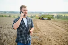 Rolnik rozmawia przez telefon na polu podczas żniw