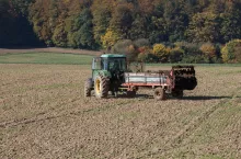 Traktor z rozrzutnikiem obornika na polu uprawnym