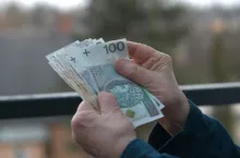 dłonie trzymające polskie banknoty stuzłotowe